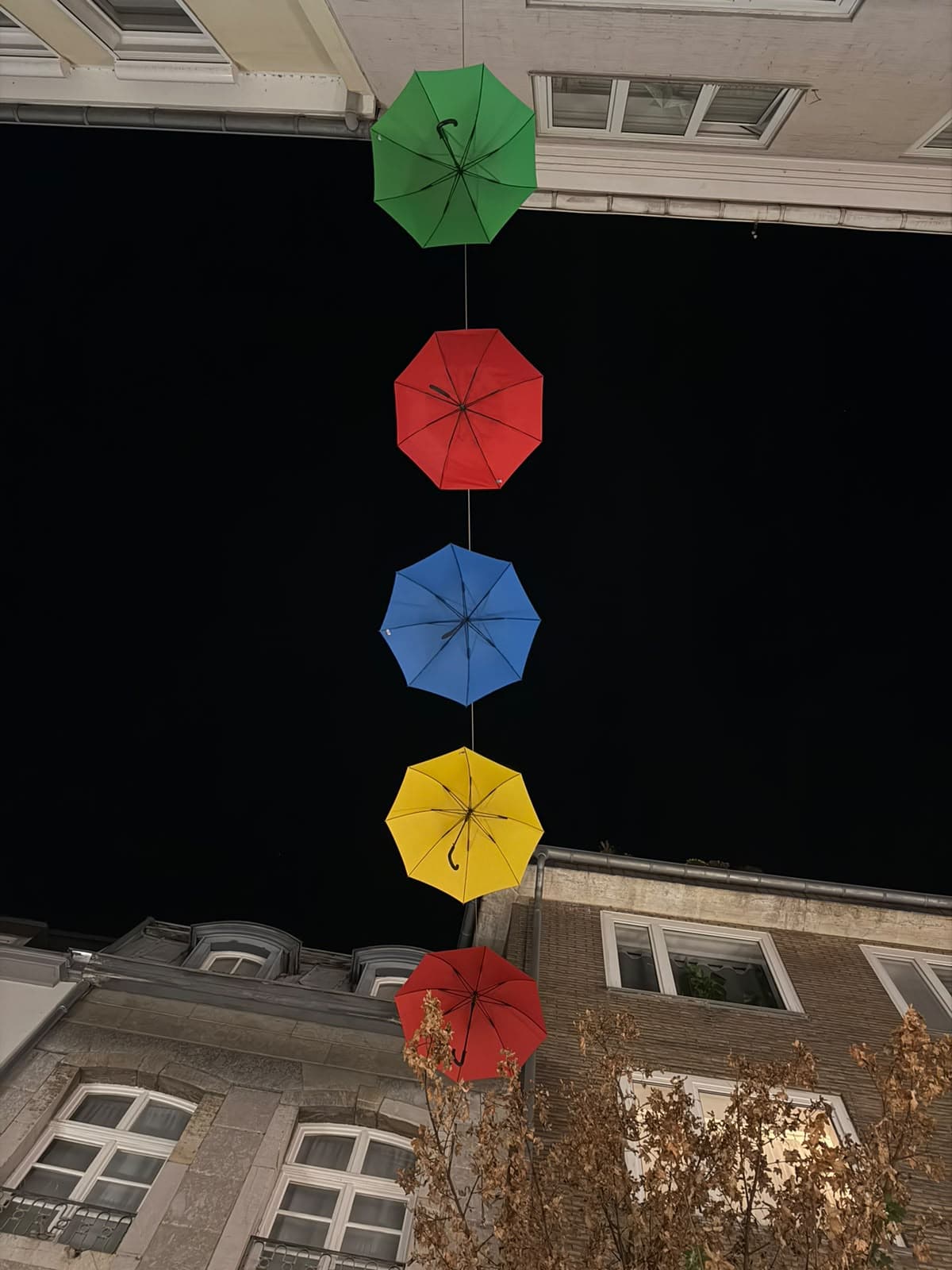 Colourful umbrellas hanging on a line above a street